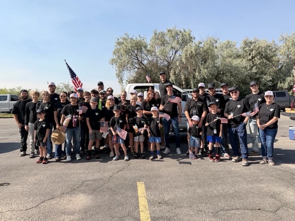 Valar Atomics team and their families holding flags before the parade