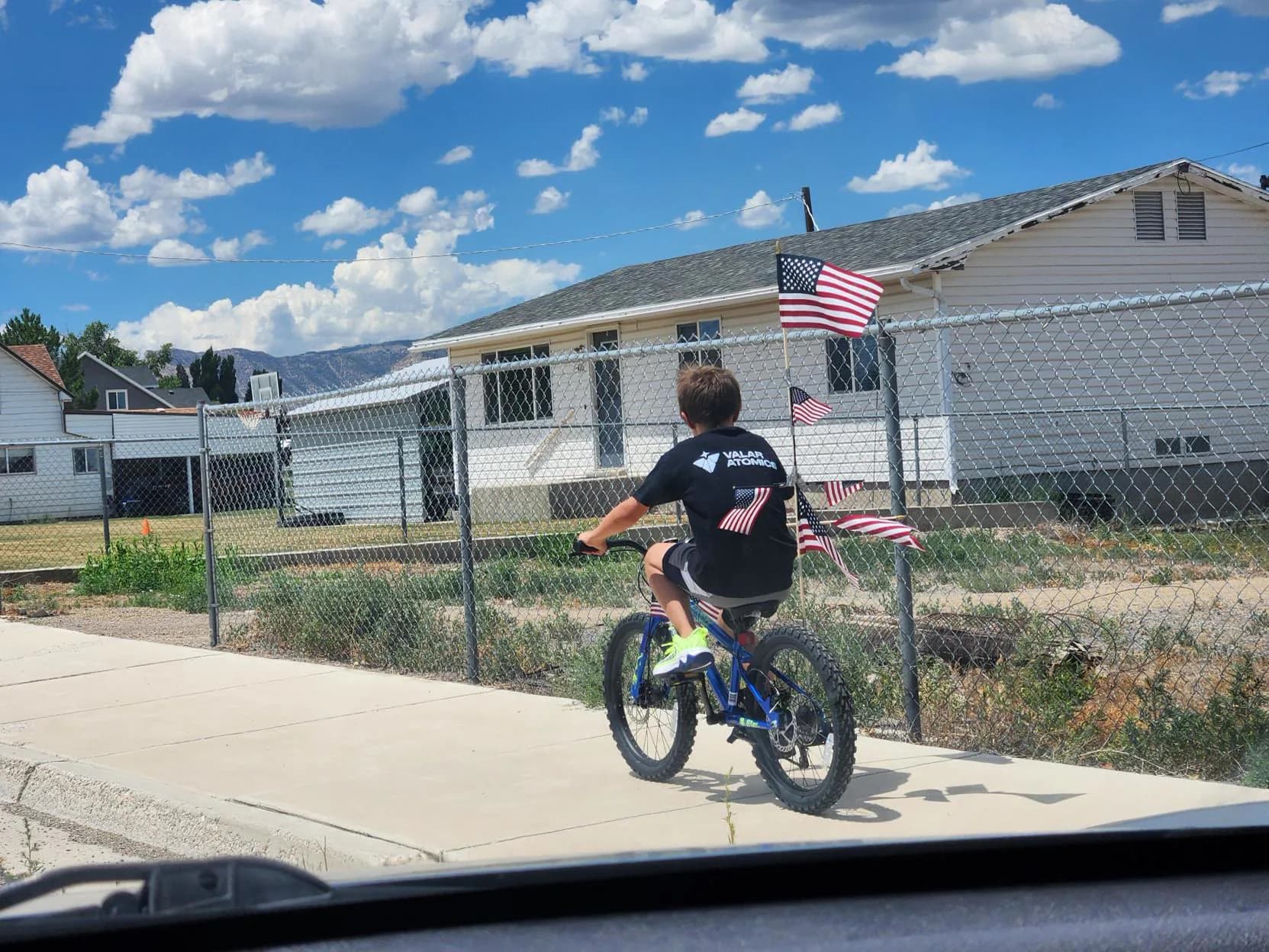 Kid riding a bike in a Valar Atomics shirt